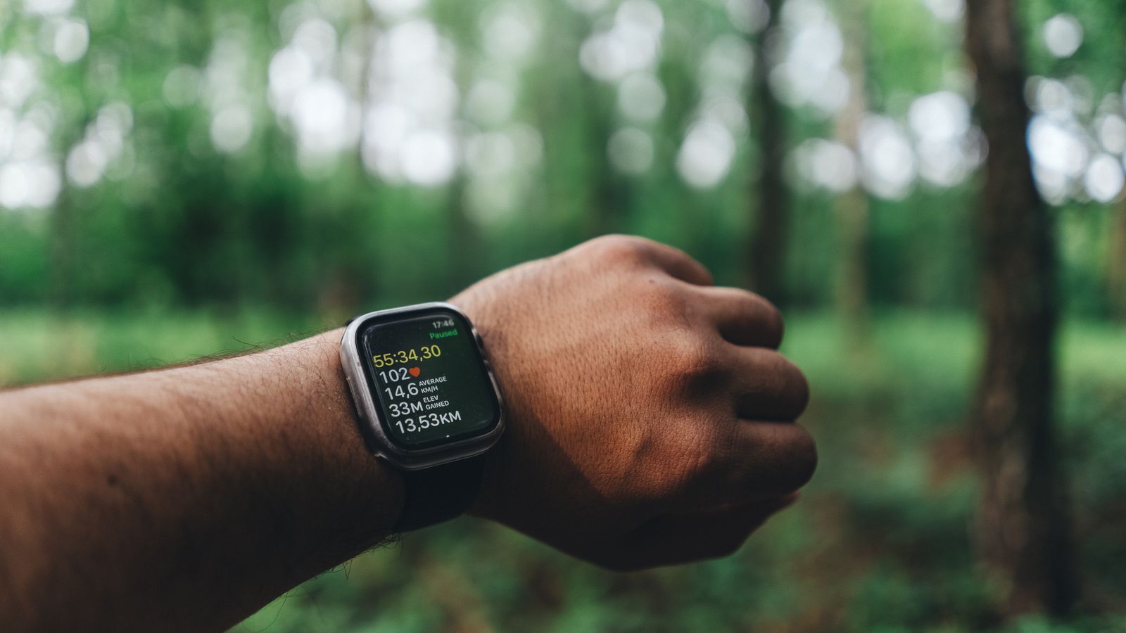 Close-up of a person's smartwatch showing running metrics outdoors.